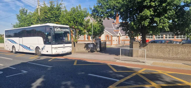White coach parked between stone gateposts